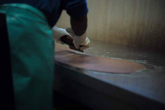 Close-up of a craftsman carefully cutting and processing cordovan by hand.