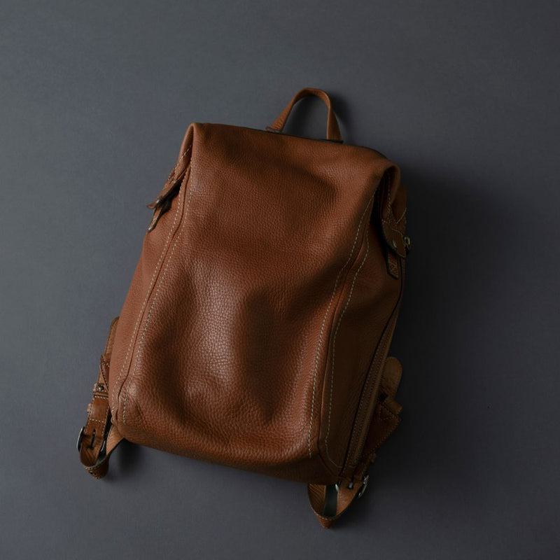Brown leather backpack on a dark gray background