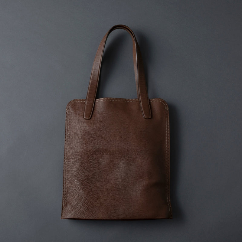 Brown leather tote bag on a dark gray background