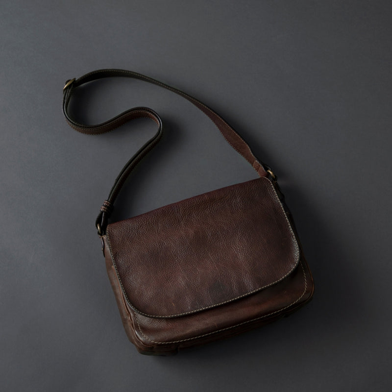 Brown leather shoulder bag on a dark gray background