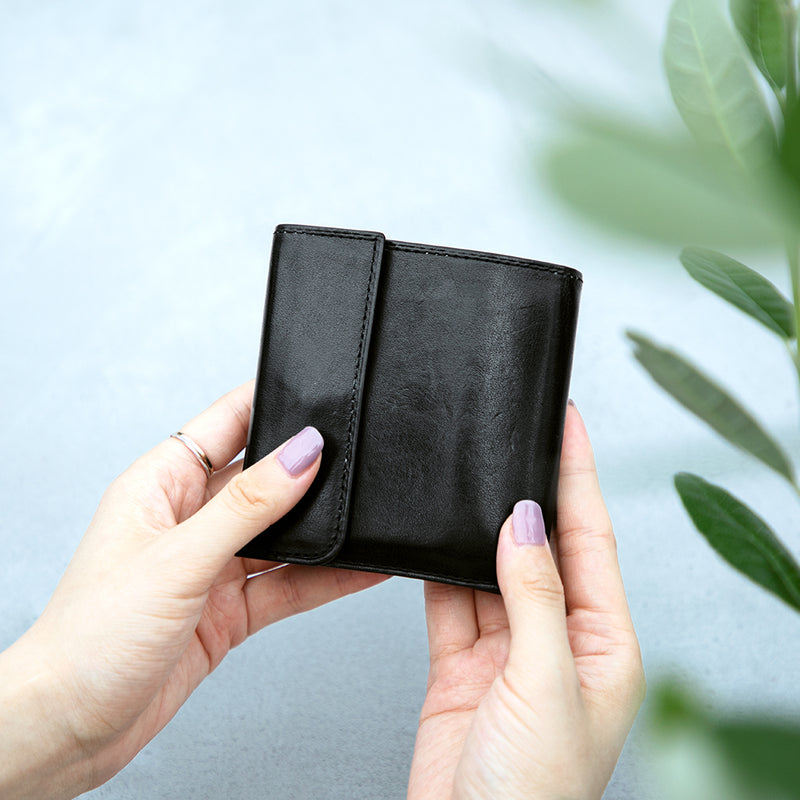 Black wallet held by a person with a light background