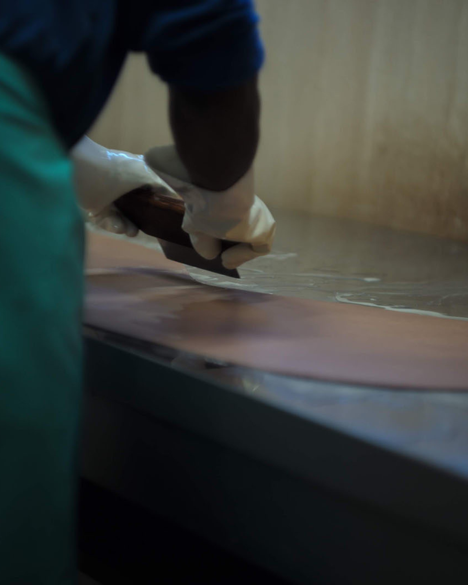 Close-up of a craftsman carefully cutting and processing glossy cordovan leather by hand.