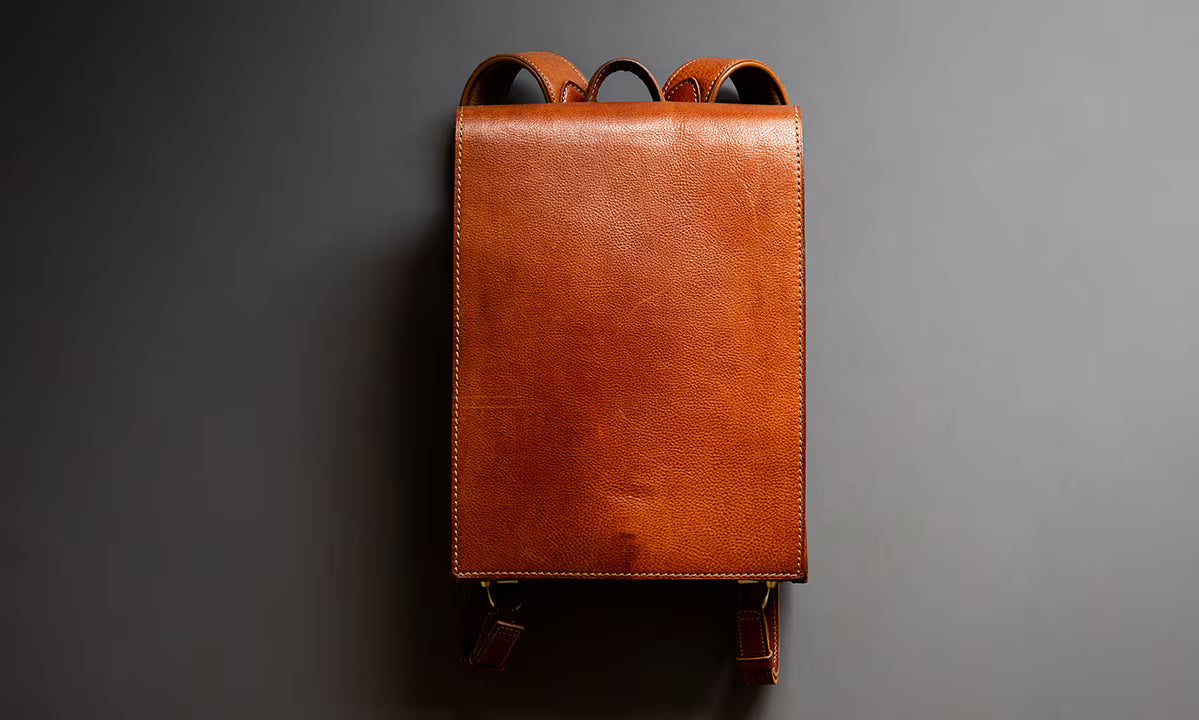 Brown leather OTONA RANDSEL backpack on a gray background