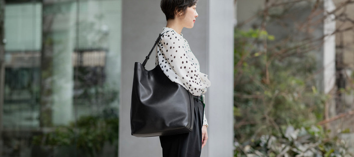 Yuka Dosaka with a luxury leather Atlow Bucket Tote leather bag in black color.