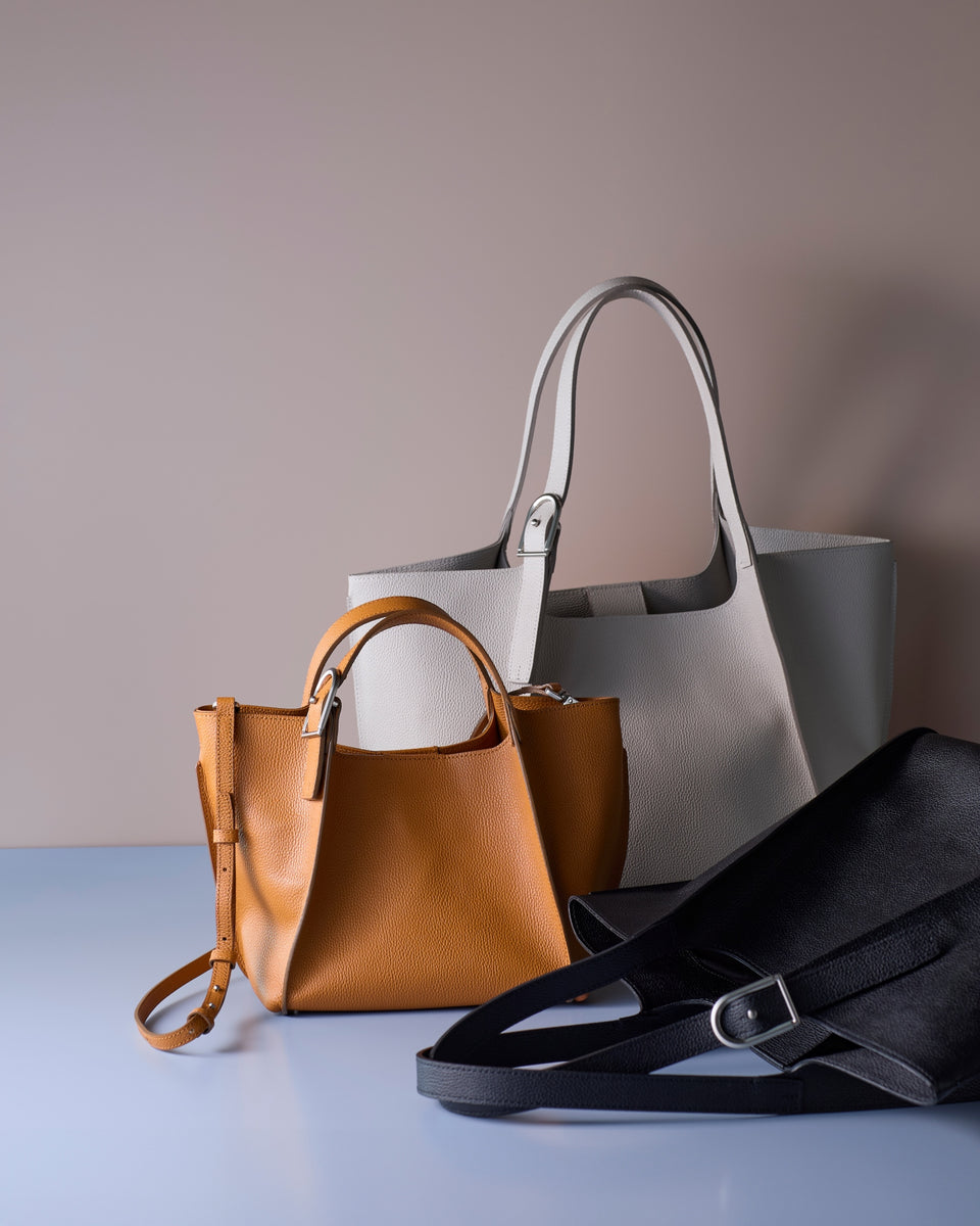 Three leather tote bags in tan, gray, and black on a light surface with a beige background: New Collection Maraison
