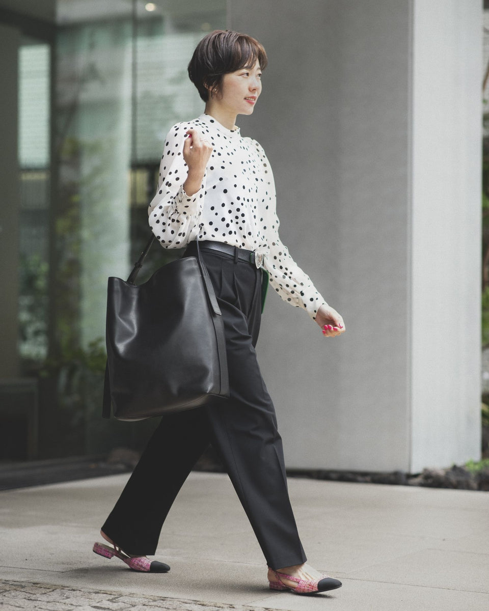 Yuka Dosaka with a luxury leather Atlow Bucket Tote leather bag in black color.