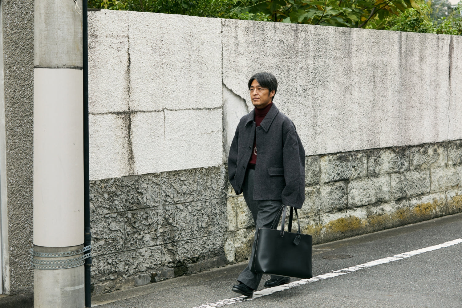 A man walking the road with TSUCHIYA KABAN's Leather bag, Diario Large Tote