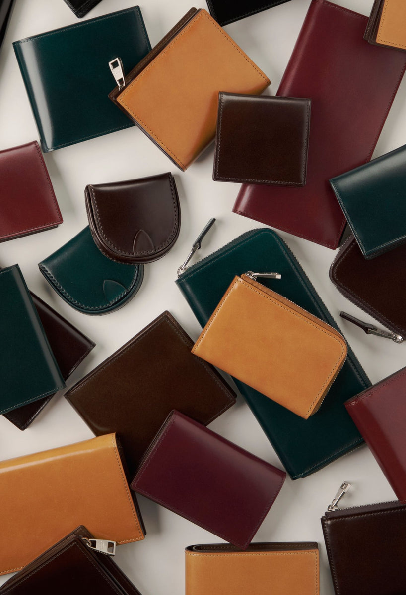 Collection of various colored Cordovan leather wallets on a white background